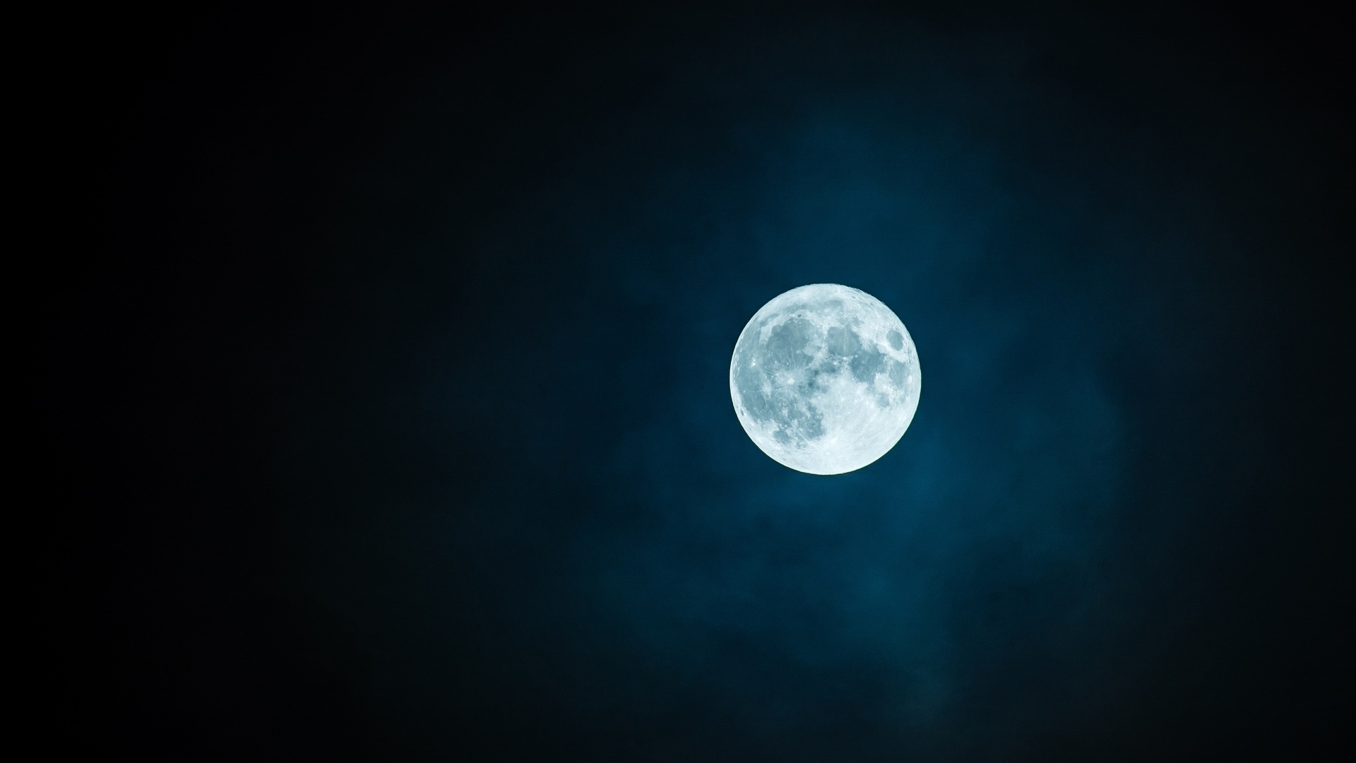 满月悬于渐变蓝黑的暗夜天空中，纹理清晰可见