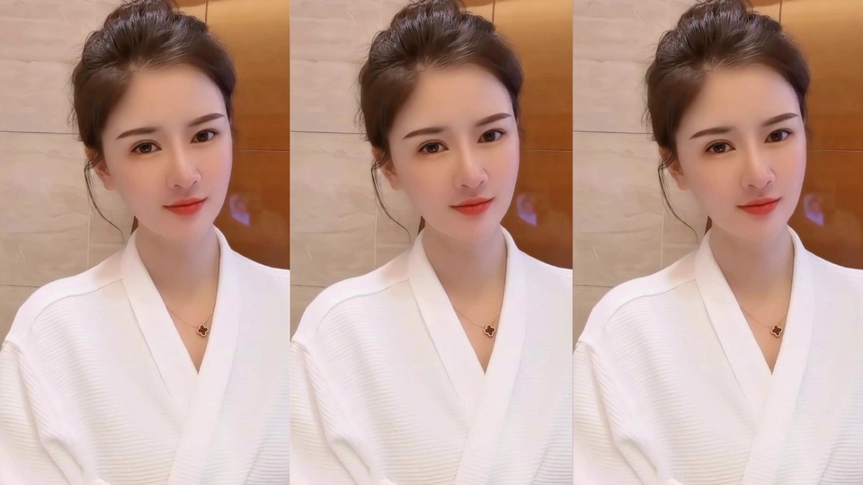 清纯人像主题写实室内居家人像，盘深色发髻的年轻女性身着白色V领肌理上衣，佩戴带深色四叶草吊坠的细项链，背景为浅米色带棕色区域的瓷砖墙面，同一张人像三等分横向重复拼接。