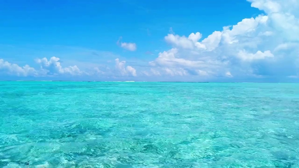 澄澈青绿色浅水海面与点缀白云的亮蓝色晴空自然海景写实画面