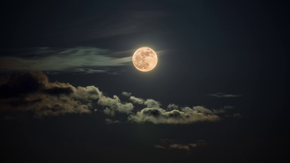 深黑夜空中悬着满月，旁侧环绕薄云，下方分布蓬松云团。