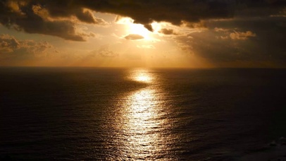 夕阳透过云层照射海面