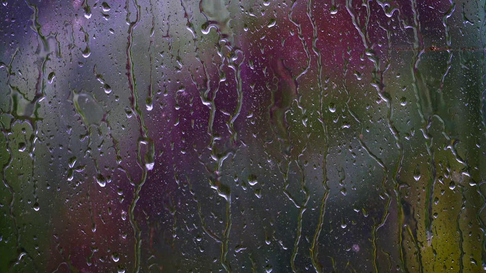 布满水珠和纵向水痕的雨天玻璃，后方是紫绿黄渐变的虚化散景。
