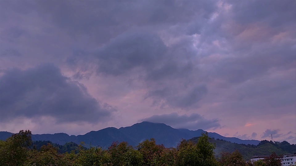 暮色山野风景，粉紫渐变天空铺满暗紫色云层，远处是深青蓝色山脉剪影，前景为茂密灌丛。