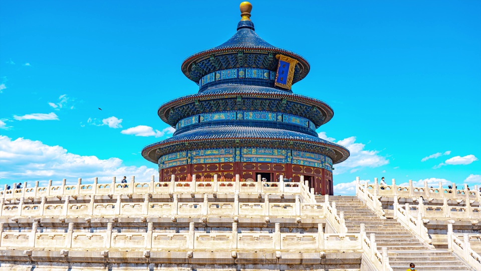 蓝天白云下的三重檐蓝瓦琉璃殿顶古典建筑，搭配多层汉白玉台基与镂空石栏杆。