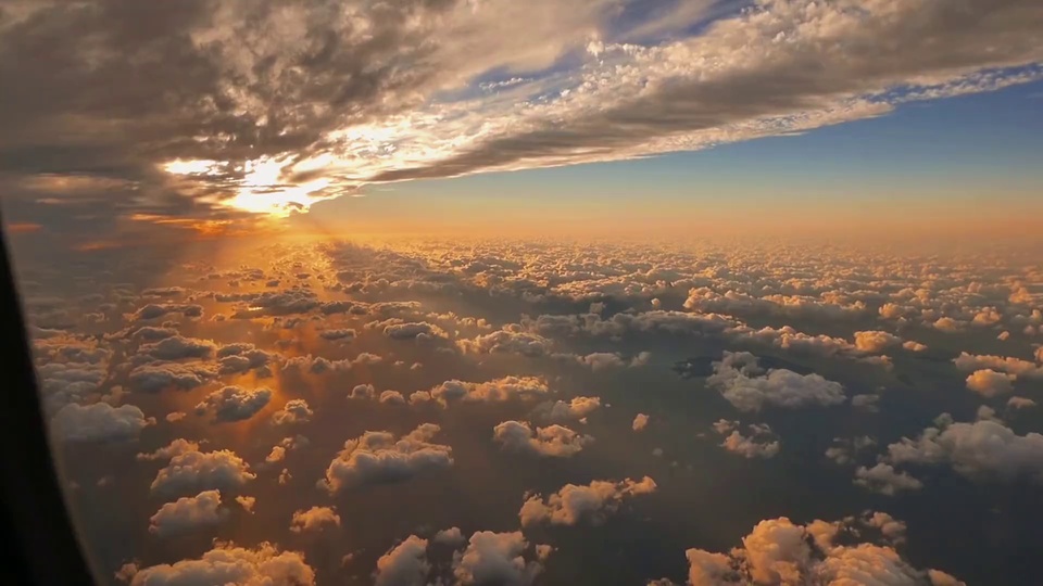 高空俯瞰日落时分的大片云海，暖金色阳光穿透云层，天际呈现暖橙到浅蓝的渐变