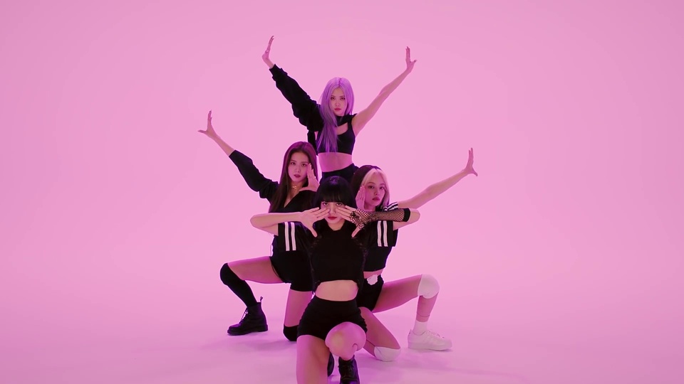 粉紫色纯色摄影棚内，blackpink、Lisa、jennie、朴彩英四名身着黑色短款露腰演出服的女性摆出同步舞蹈姿势。