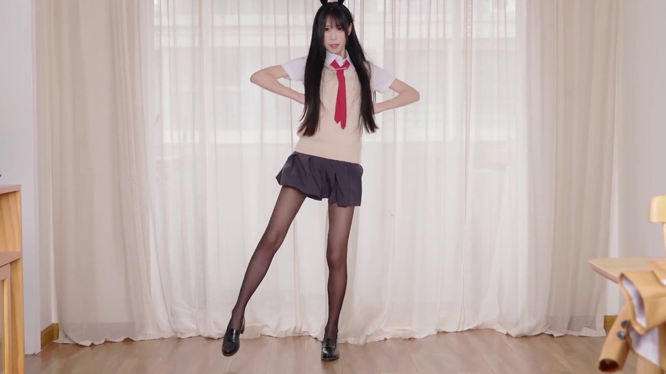 留黑色长直发的年轻女性，头戴黑色兽耳发饰，身着白衬衫、米色针织背心、红领带、深灰百褶短裙、黑丝袜与黑皮鞋，双手放在腰后摆出舞蹈姿势，身处铺有浅棕木纹地板、悬挂半透米白纱帘的室内空间。