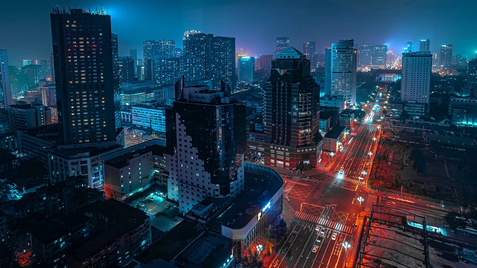 蓝橙撞色赛博风都市夜景，高低错落的摩天楼间主干道车流灯轨蜿蜒，冷调蓝辉晕染雾感夜空。