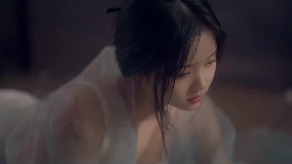浅景深画面中，身着浅白半透明古风纱衣的黑发盘起女子低头垂目，背景为模糊暗调室内场景，整体笼罩着忧郁氛围。