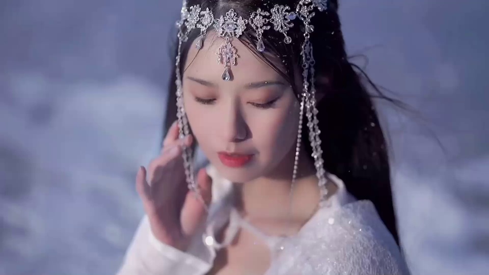 淡蓝雪景中佩戴银白水晶流苏头饰的白衣女子近景