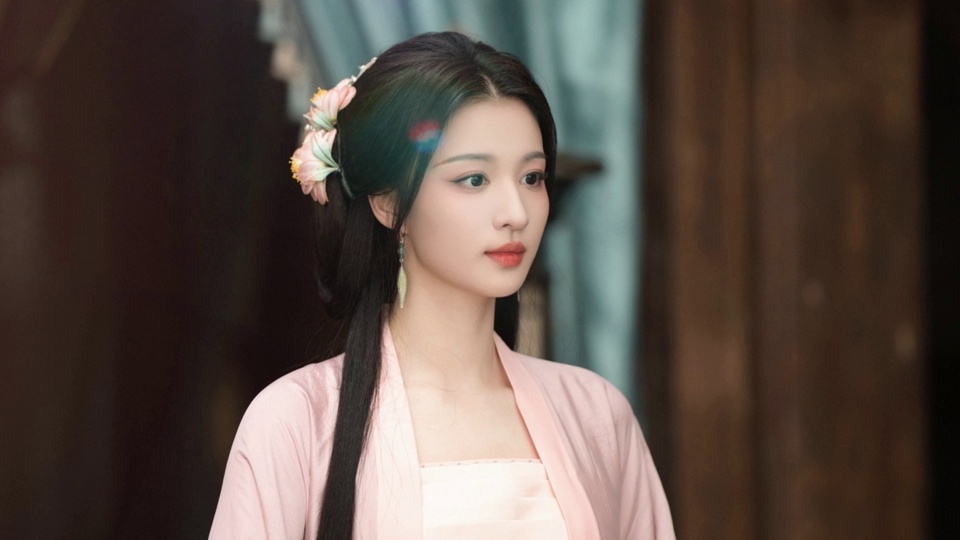 浅粉色古装古风女性侧望画面右侧，佩戴带绿坠的长款耳饰与粉黄花朵发饰，背景是虚化的深棕色木柱与浅青色布艺帘。