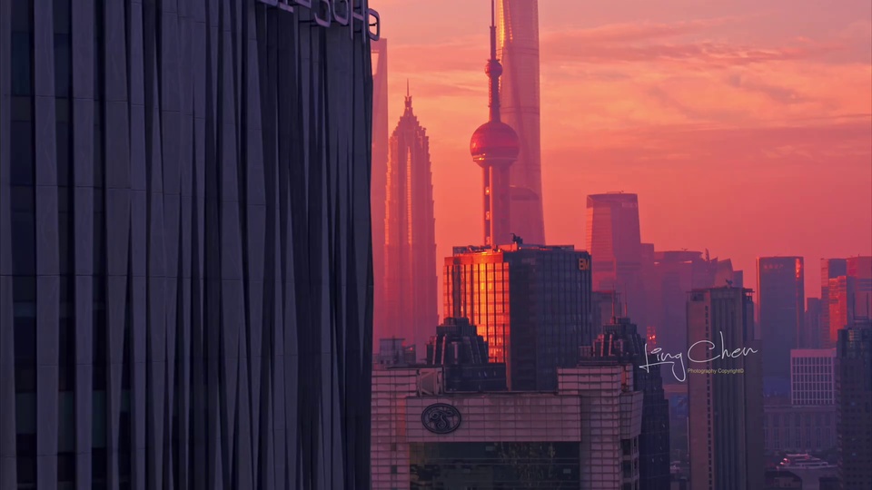 橙粉色暮色笼罩的上海城市天际线，左侧深色高楼立面向前延伸，多座摩天楼错落排布。