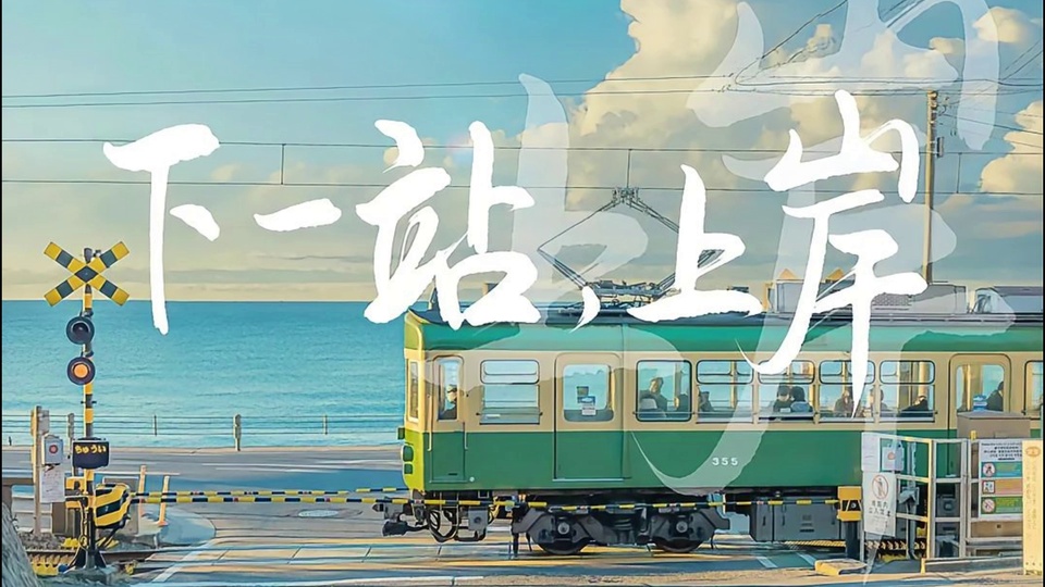 停靠在海边铁路道口的绿黄相间有轨电车，背景是蓝绿色海面与飘着柔白云朵的淡蓝色天空