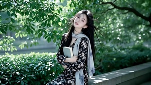 绿化花坛边看书的长发美女