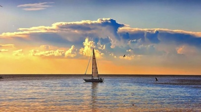黄昏下的大海平静海面帆船驶来