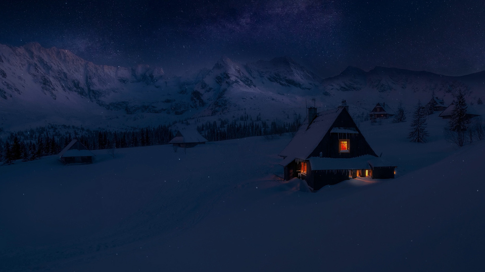 冬日雪夜山地，雪坡散落暖光木屋，天幕布满繁星与银河，远处是连绵雪山。