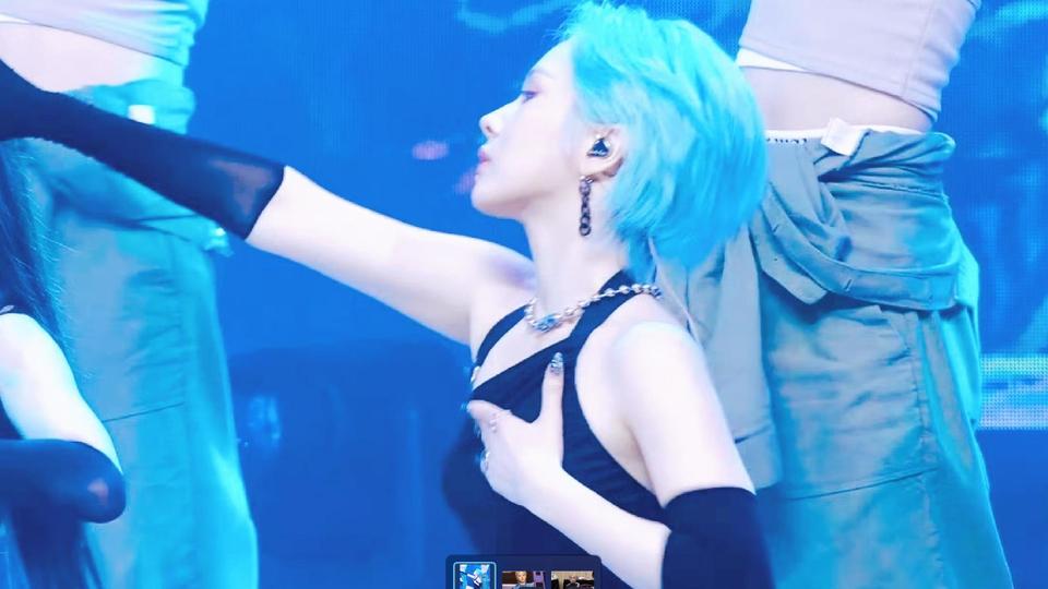 冷蓝色灯光舞台上的蓝发短发女表演者，黑色挂脖上衣搭配链条配饰