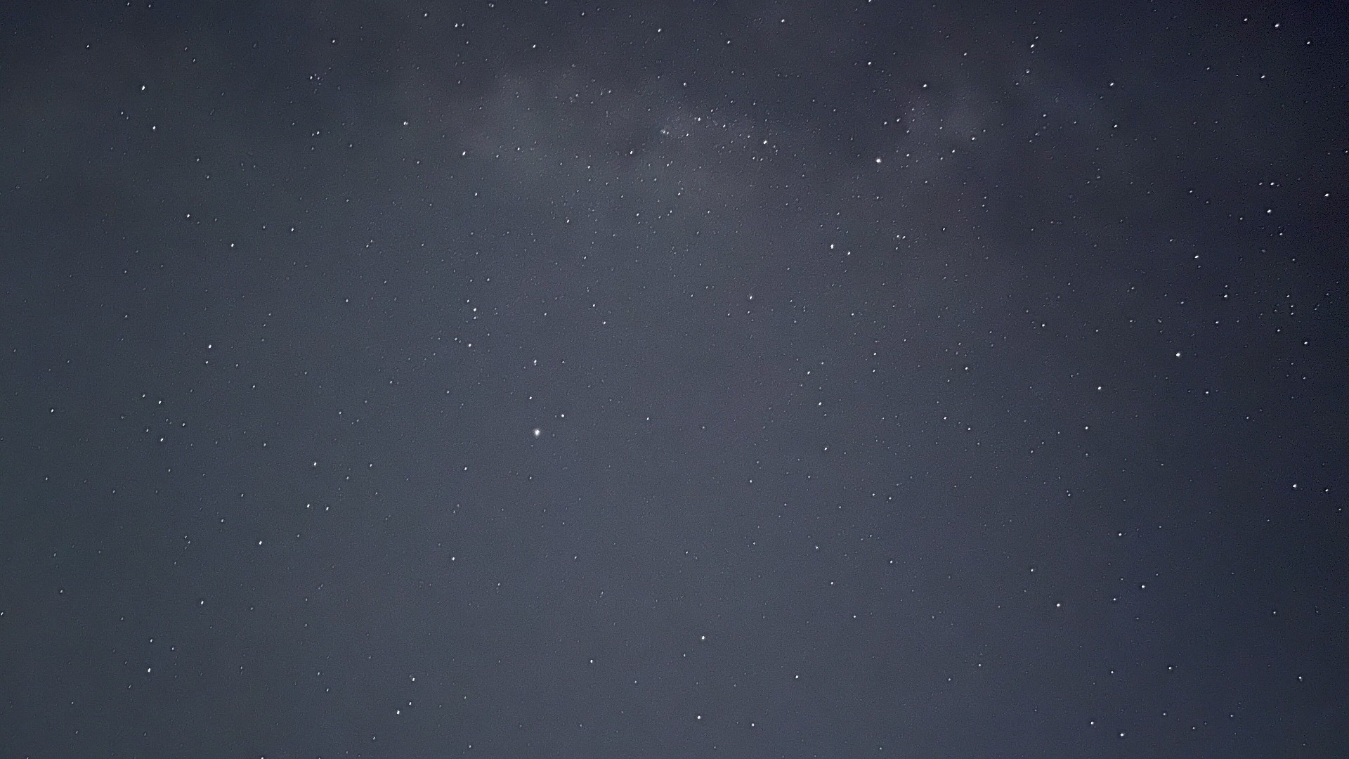 深灰蓝色夜空布满细碎亮白星点，上部有淡雾状朦胧星带