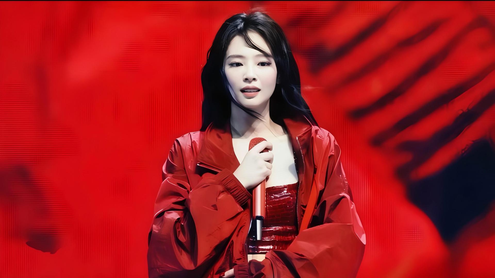 jennie留黑色长发，身着亮面红色宽松外套与红色鳄鱼纹抹胸，手持红色麦克风，站在红色调纯色舞台背景前。