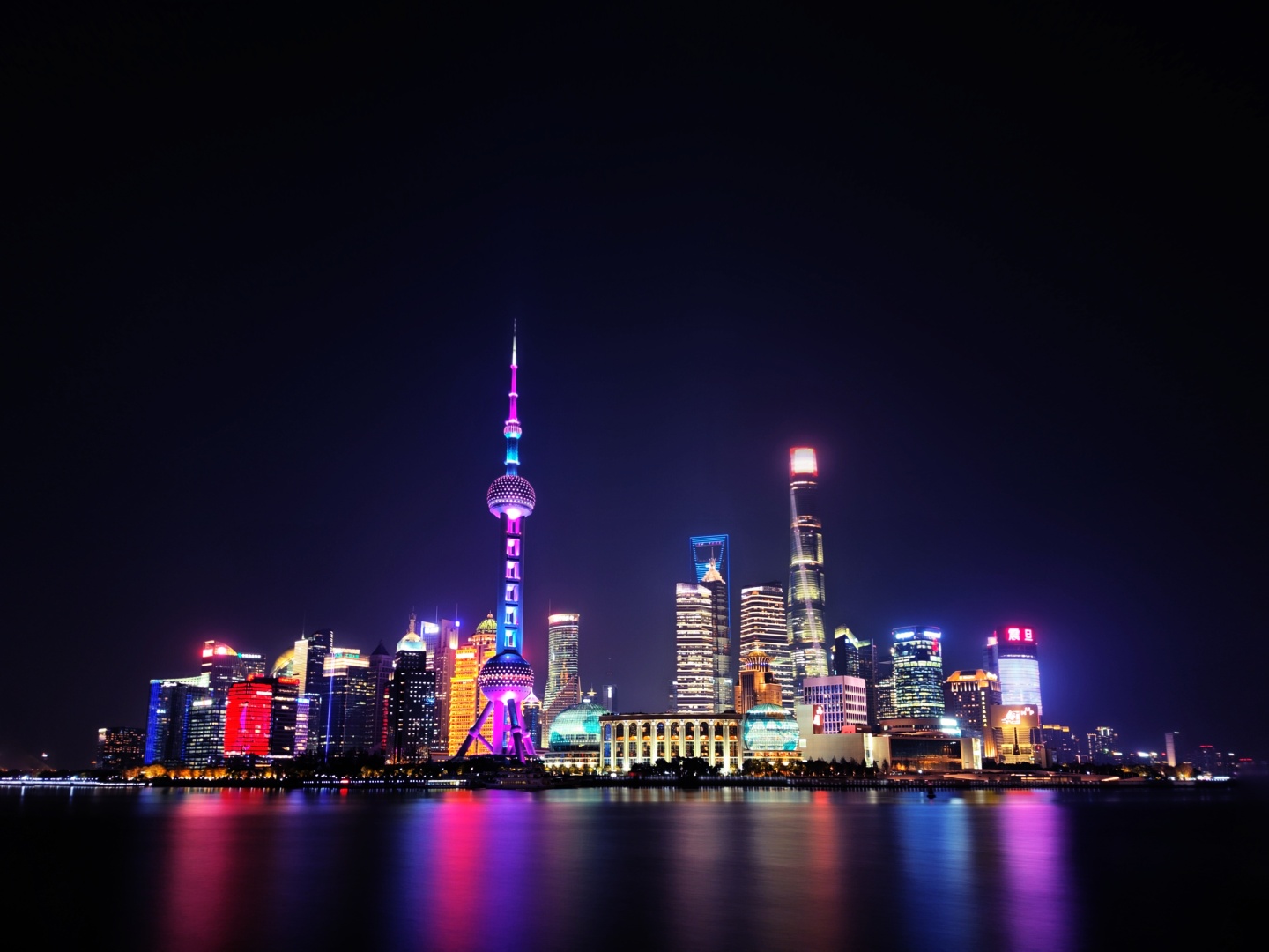 滨水都市夜景，多彩摩天楼群的灯光在平静水面映出绚丽倒影。