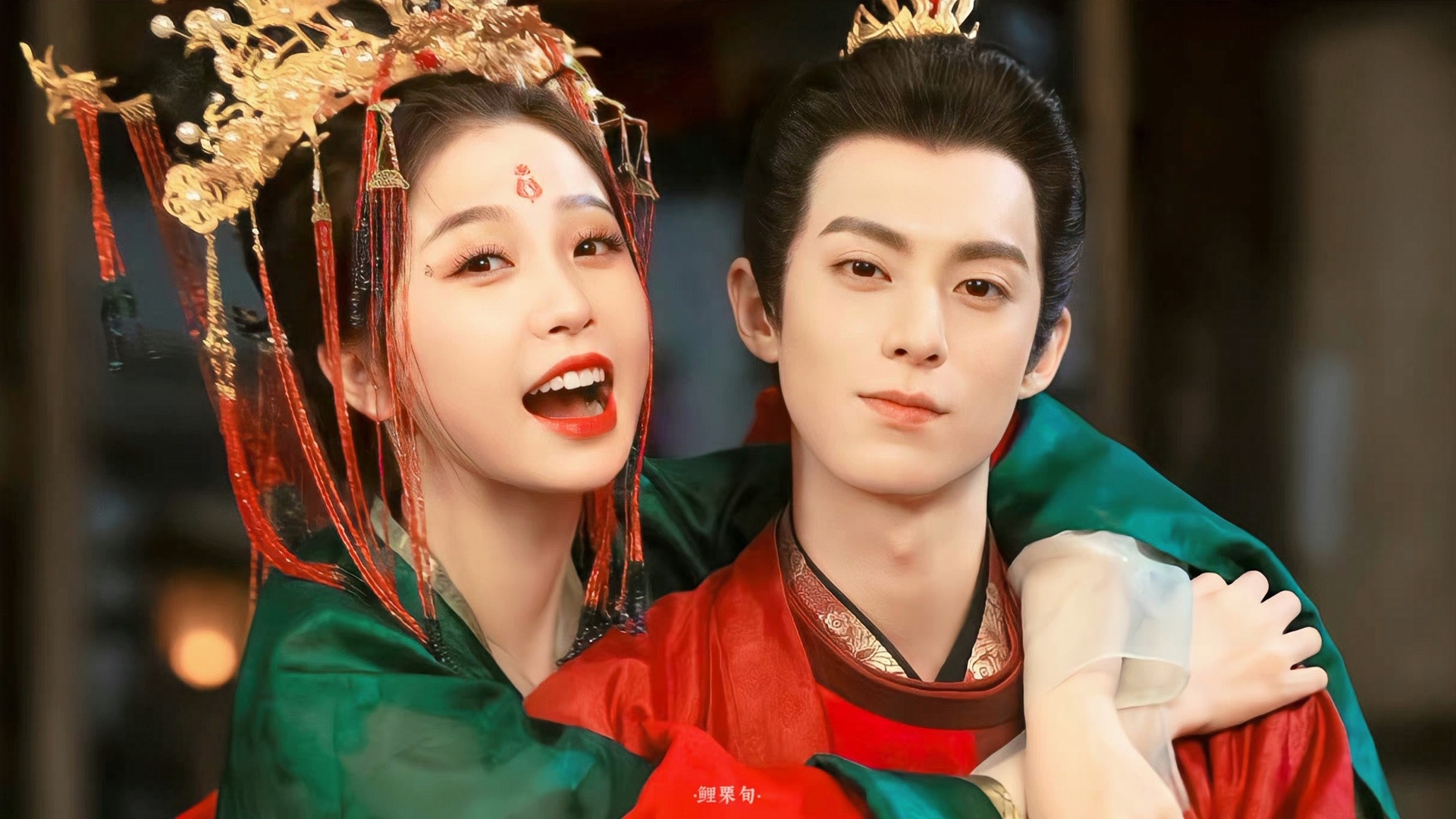 身着红绿古装的男女相拥，女子妆容精致神态明快。