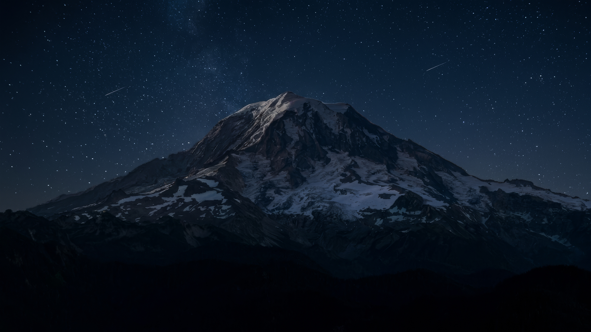 星空下积雪覆盖的山脉矗立在暗夜里